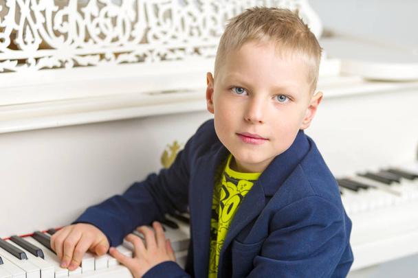 Little boy in studio near white piano. - Valokuva, kuva