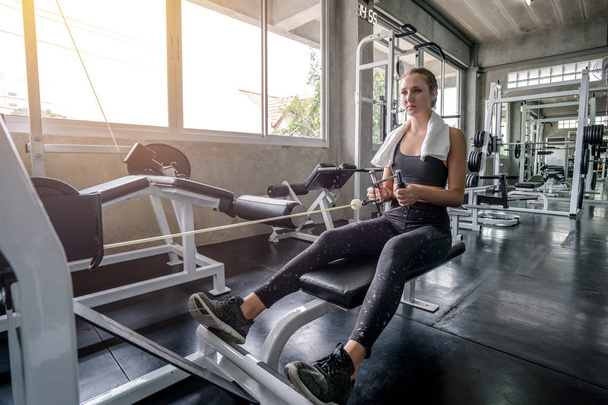 Mujer joven bajando el peso de la máquina de fitness y haciendo ejercicio i
 - Foto, imagen