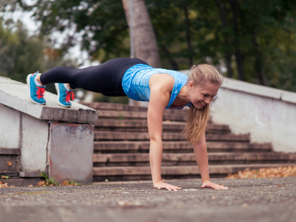 Caucasian girl doing street workout into the park outdoor in summer, plank pose, selective focus - Photo, image