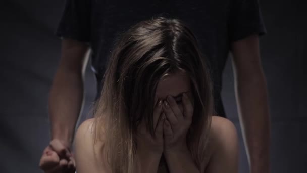 agresión y violencia doméstica, llorando niña cubrió su cara con las manos contra el fondo del marido de pie detrás de ella con un puño
 - Metraje, vídeo