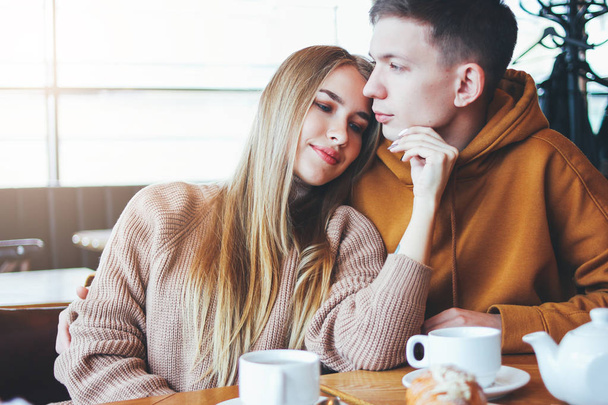 Nuori pari pukeutunut lämmin rento vaatteet istuu kahvilassa yhdessä
 - Valokuva, kuva
