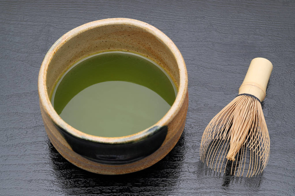 Chá verde matcha japonês em uma tigela de cerâmica com batedor de chá
 - Foto, Imagem