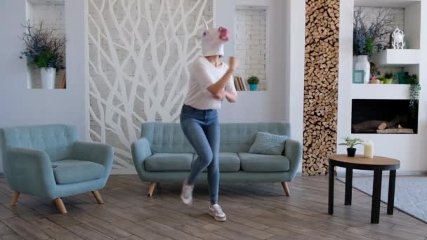 Strange funny video: woman in a mask of unicorn dancing in the living room at home - Materiał filmowy, wideo