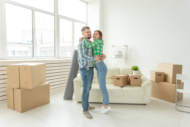 Relocation, real estate and moving concept - Young cheerful couple moving into their new home - Foto, afbeelding