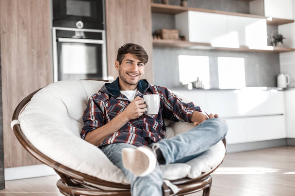 attractive guy with a Cup of tea sitting in a bright kitchen - Фото, изображение