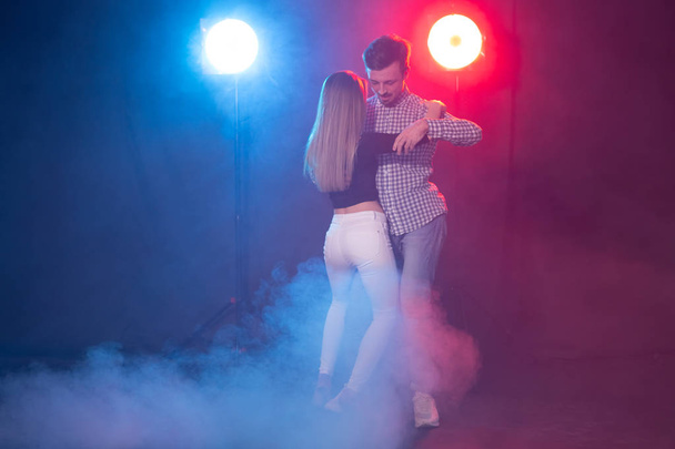 Baile social, bachata, salsa, kizomba, zouk, concepto de tango - Hombre abraza a mujer mientras baila sobre luces
 - Foto, imagen