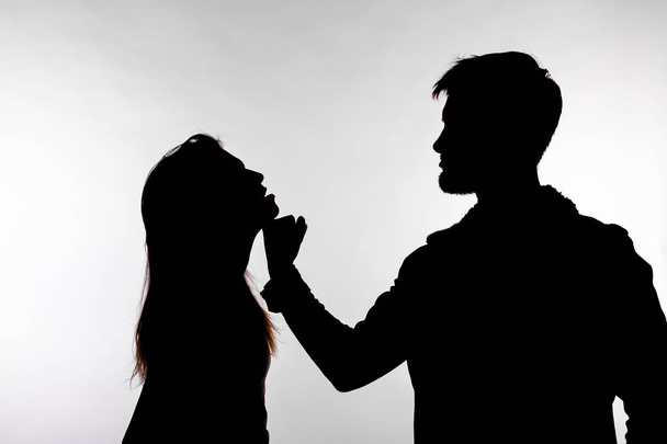 Concetto di aggressione e abuso - uomo e donna che esprimono violenza domestica nella silhouette dello studio isolati su sfondo bianco
. - Foto, immagini
