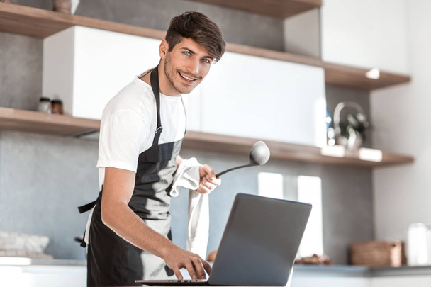 young man reading a recipe for soup in a laptop - Foto, afbeelding
