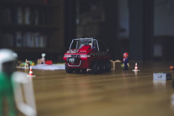 Close shot of a red toy vehicle with figurines on a wooden surface with a blurred background - Valokuva, kuva