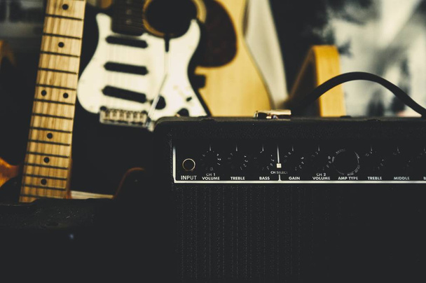 Selective shot of a black amplifier near a black electric guitar - Foto, Imagen