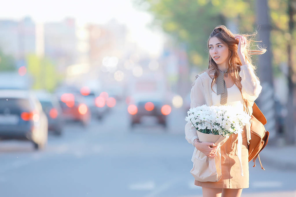 happy girl with flowers in the city / summer photo young beautiful girl holding a bouquet of flowers on a city street - Photo, Image
