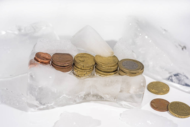 氷の中で冷凍ユーロ硬貨。銀行の抽象的な写真. - 写真・画像