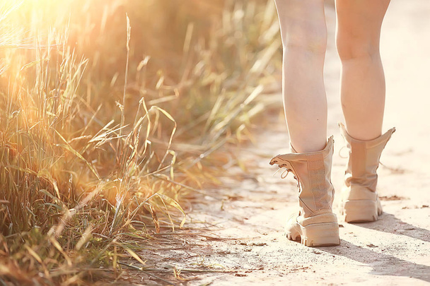 female legs in summer trekking boots / walks anonymously on the field woman big shoes girl - Photo, Image