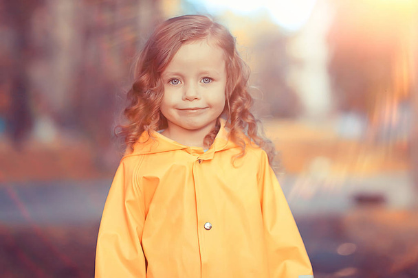 little girl in a yellow raincoat / portrait of a child in autumn clothes, a walk in the rain - Foto, afbeelding