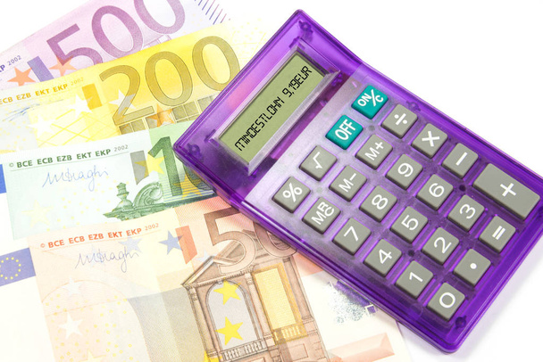 Банкноты евро и калькулятор, указывающие на минимальную заработную плату 9,19 евро в Германии
 - Фото, изображение