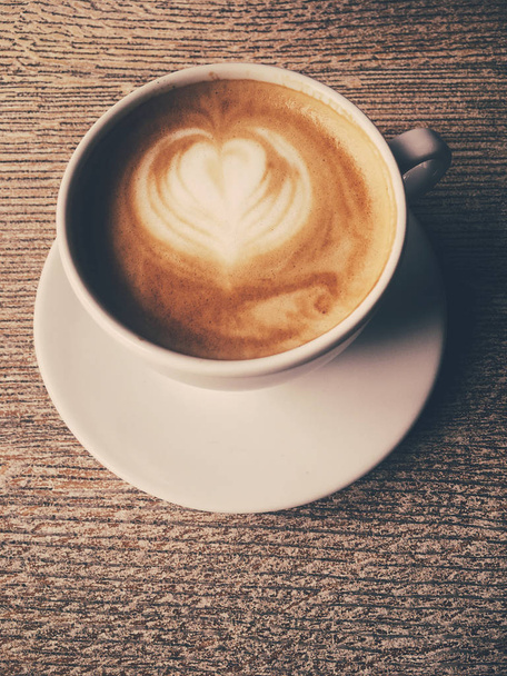 Kuppi kuumaa cappuccinoa kahvilassa, kahvia puupöydällä i
 - Valokuva, kuva