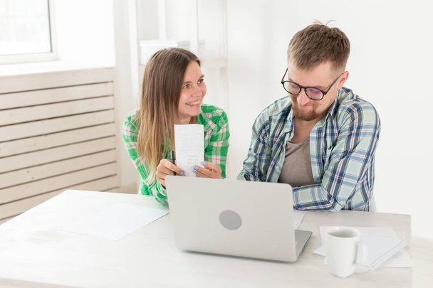 Dissatisfied young husband and wife recount utility bills for payment of an apartment and write the results in a notebook and laptop in their home accounting. - Φωτογραφία, εικόνα