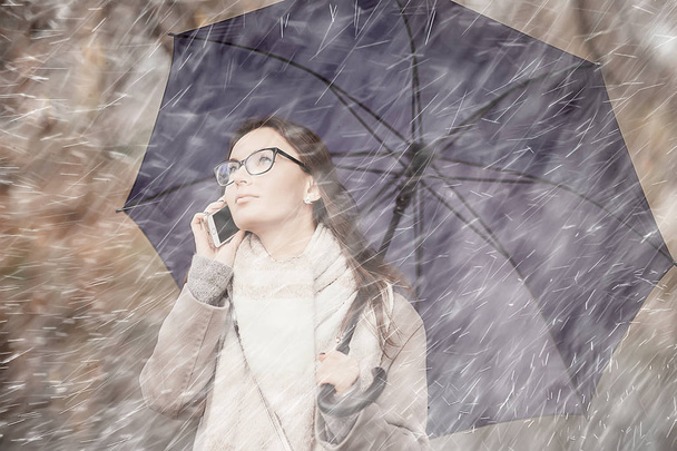 woman talking on the phone in the fall rain / autumn weather message about the rain, a model with an umbrella - Photo, Image