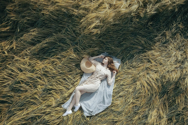 girl lies in a wheat field top view / summer vacation relaxation freedom, picnic in nature view from a copter - Zdjęcie, obraz