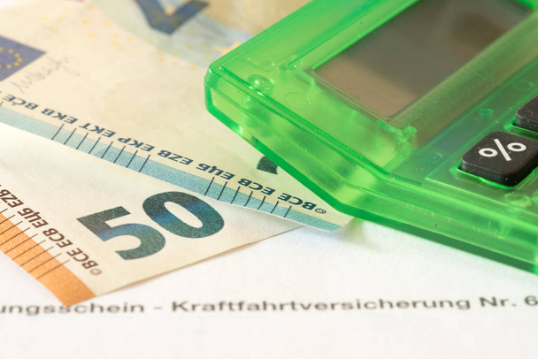 Banconote in euro, calcolatrice e certificato assicurativo per un'assicurazione auto
 - Foto, immagini