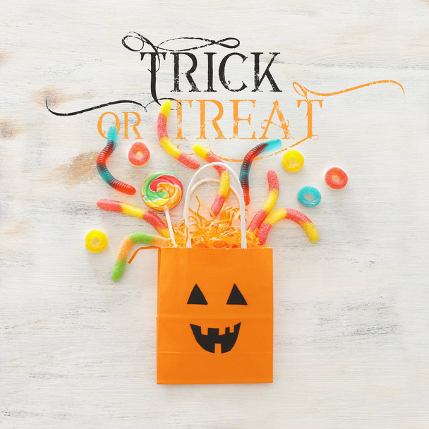 holidays image of Halloween. paper gift bag and sweets over wooden white table. top view, flat lay - Valokuva, kuva