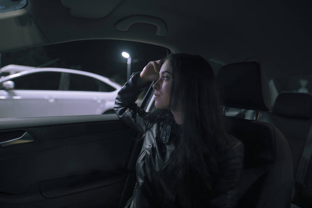 Woman in a car looking at window, night time - Foto, afbeelding