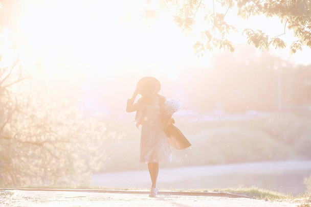 Mädchen, das auf ein Date in der Stadt wartet / glückliches Mädchen mit einem Blumenstrauß, das in der städtischen Landschaft spaziert, weiches Licht - Foto, Bild