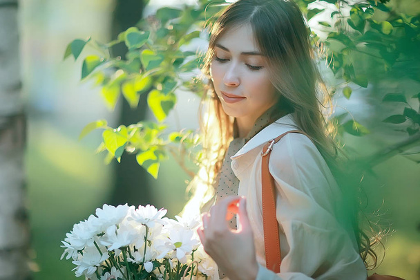 girl holding a bouquet of flowers a walk in the park / romantic young beautiful cute model, love feelings gift - Фото, изображение