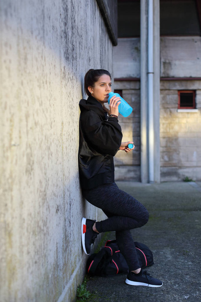 Urban sporty woman drinking water. - Foto, afbeelding