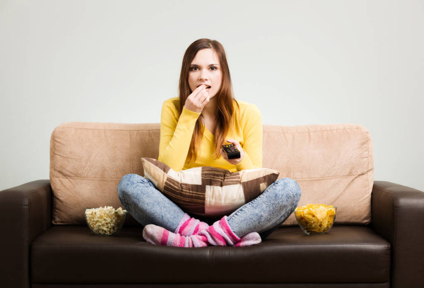 Young woman spends his free time watching TV on the couch at hom - Photo, image