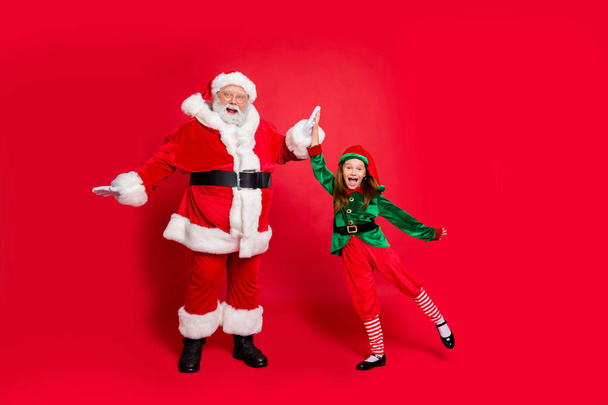 Full size photo of crazy santa claus elf having headwear eyewear eyeglasses spectacles celebrate success on noel preparation wearing green costume isolated over red background - Photo, Image