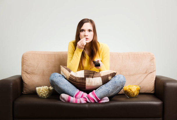 Young woman spends his free time watching TV on the couch at hom - 写真・画像