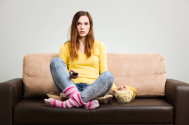 Young woman spends his free time watching TV on the couch at hom - Foto, immagini