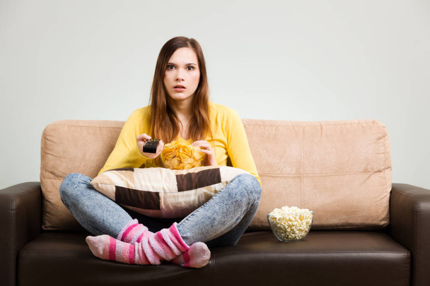 Young woman spends his free time watching TV on the couch at hom - Foto, Imagem