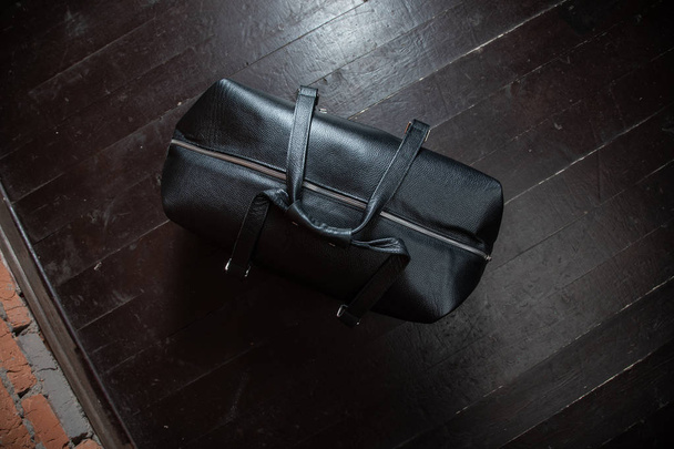 Men's accessories with black leather bags on wooden floor over wall background - Fotoğraf, Görsel