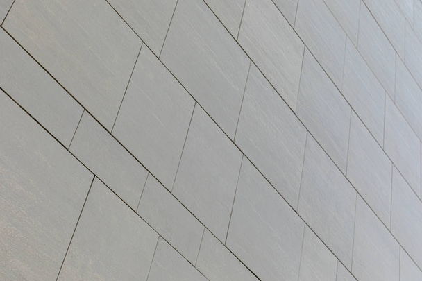 Χαμηλή γωνιακή άποψη τοίχου με γκρίζα λεία πλακάκια διαφορετικού σχήματος (ορθογώνια και τετράγωνη) - Φωτογραφία, εικόνα