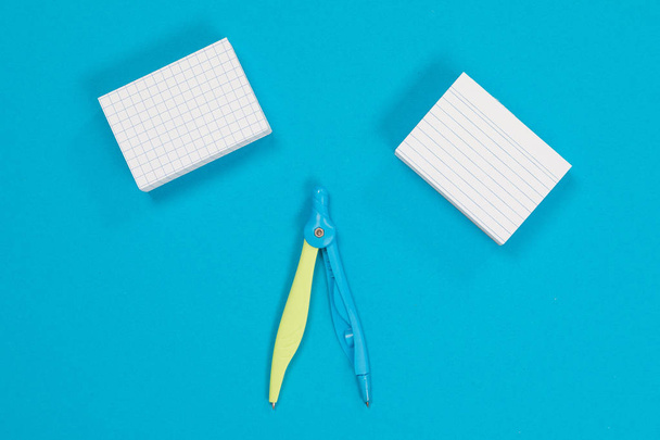 Two stacks of white post-it and a compass in the middle on azure surface isolated - Photo, Image