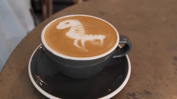 Κορυφαία θέα από καφέ ζεστό καφέ ή καπουτσίνο σε φλιτζάνι με καφέ με γάλα σε ξύλινο φόντο τραπεζιού - Πλάνα, βίντεο