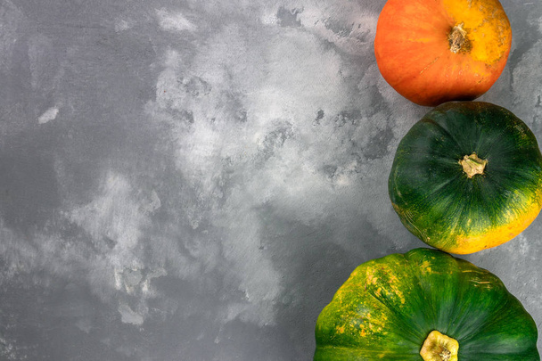 Herbstkomposition mit grünen, gelben, roten und orangefarbenen Kürbissen auf grauem Zementhintergrund. flache Lage, Draufsicht, Kopierraum - Foto, Bild