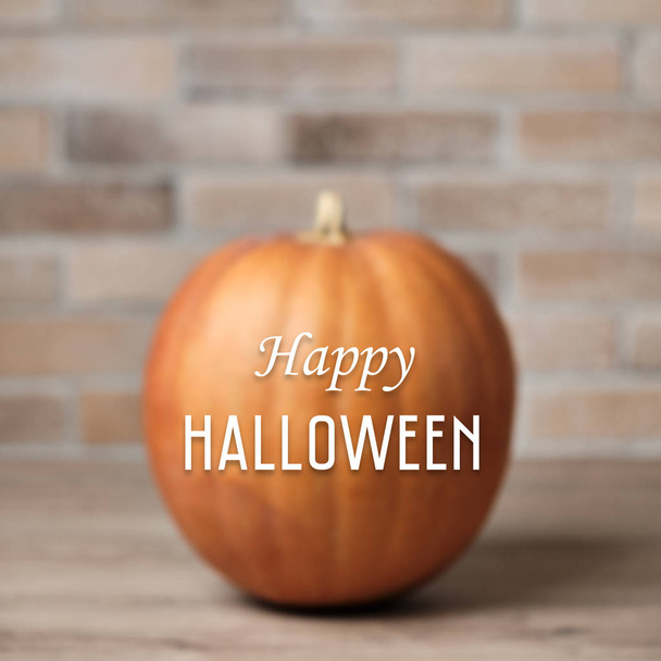 Halloween háttér a koncentrált sütőtök ellen téglafal és boldog halloween betűkkel - Fotó, kép