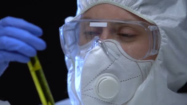 Woman in protective mask and respirator demonstrating inflammable liquid in tube - Materiał filmowy, wideo