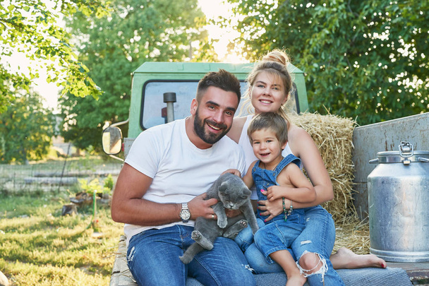 familia con hijo y gato junto a una camioneta en verano al atardecer
 - Foto, imagen