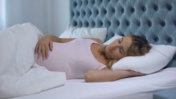 Kobieta w ciąży śpi spokojnie w łóżku, głaskanie brzucha, zdrowa matka i płód - Materiał filmowy, wideo