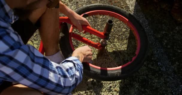 Overhead low section view of a young Caucasian man repairing the wheel of his BMX bike - Filmmaterial, Video