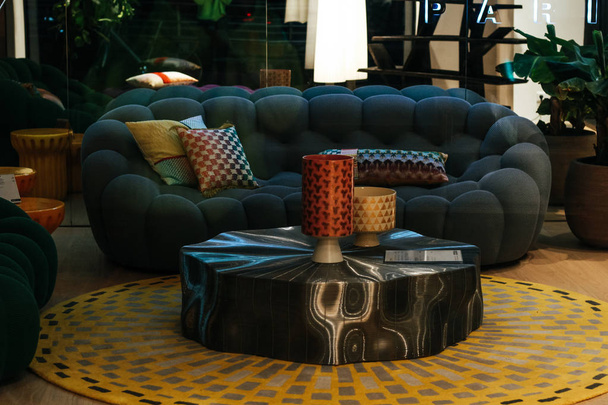 Стильний диван, стіл і лампи. Темно-синій диван. Подушки зі сквоєю
 - Фото, зображення