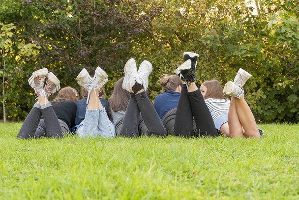 Зображення ніг і взуття молодих дівчат-підлітків, що стоять на траві парку. Насолоджуйтесь щасливим моментом і ідеальним місцем. Розважатися і насолоджуватися дружбою. Концепція єдності та різноманітності
. - Фото, зображення