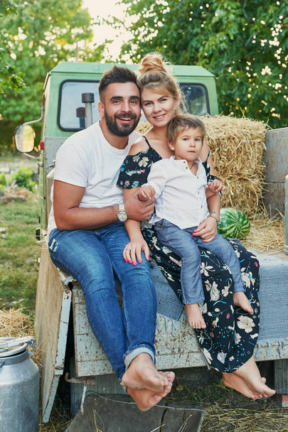 family with watermelons at the harvest next to a pickup truck in summer at sunset - Foto, Imagen