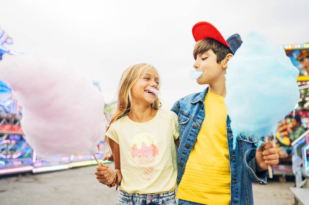 Мальчик и девочка едят сладкий хлопок в парке развлечений
 - Фото, изображение