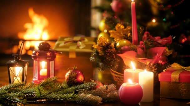 Oturma odasında şömine yanan Closeup 4k görüntüleri ve mumlar, süs eşyaları ve Noel hediyeleri ve hediyeler ile dekore edilmiş güzel bir tablo. Kış kutlamaları ve tatiller için mükemmel çekim - Video, Çekim