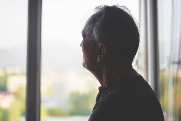 Silhouette of an elderly man on a window background. Old age. Depression pensioner. Retirement loneliness. - Φωτογραφία, εικόνα
